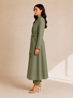 Aria Prestige Belted Coat by WAROODI side view, full-length sage green crepe-wool blend coat with long sleeves, fluid A-line drape, side pocket detail, and luxury modest styling.