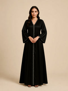 Layali Black Satin Embellished Kaftan by WAROODI front view, full-length modest black kaftan with V-neckline, crystal-trim detailing, embellished front panel, wide sleeves, and flowing A-line silhouette.