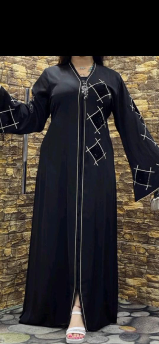 Black abaya with white patterns on a textured wall background
